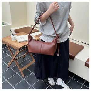 Close-up of brown leather crescent shoulder bag with knot detail and metal bead accent