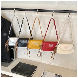 Gros plan sur cinq sacs à bandoulière papillon brodés en argent, noir, jaune, rouge et beige