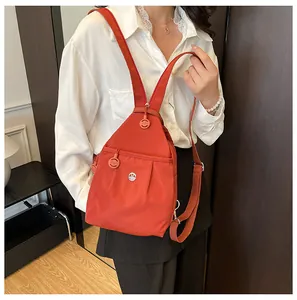 Detail of orange-red sling backpack with metal M logo and high-density nylon texture