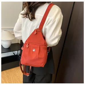 Detailed close-up of a bright red nylon crossbody bag showing the front zipper pocket and logo
