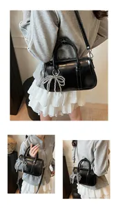 Detailansichten einer schwarzen Boston Bag mit großem Perlen-Schleifen-Anhänger-Detail