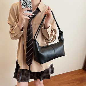 Minimalist black tote bag with knot shoulder strap and silver zipper in studio shot