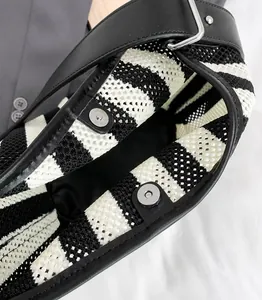 Detail van de metalen magnetische gesp en voering op de gestreepte gebreide tas