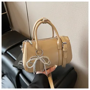 Detail der beigefarbenen Boston Bag mit Perlenbogen Anhänger und verstellbarem Gurt