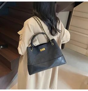 Detail of a black quilted leather tote bag featuring gold chain strap and twist lock buckle