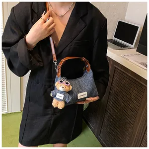 Details der Denim-Umhängetasche mit Lederbesatz und süßem Bären-Schlüsselanhänger