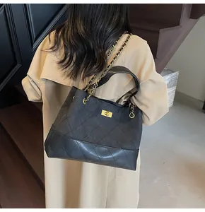 Detail of black quilted leather tote bag with gold chain strap and turn-lock closure