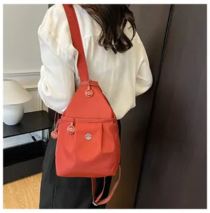 Close-up of orange-red waterproof nylon backpack with metal M logo and adjustable straps