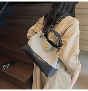 Chic quilted tote with grey suede and black leather paneling worn by a model