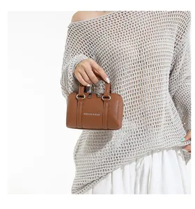 Detailed shot of a brown mini cylinder handbag with white logo and silver hardware