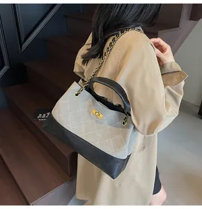 Detail of two-tone quilted tote with gold turn-lock and chain strap on vintage stairs