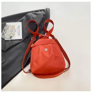 Detail of the orange nylon mini backpack with a pleated design and metallic logo