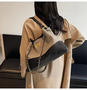 Quilted tote bag with gold chain strap and gray-black patchwork shown on trench coat