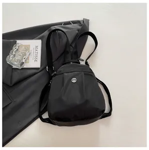Detail of black nylon mini backpack with silver M logo alongside Matisse art book