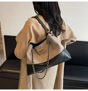 Detail of quilted tote bag with chain strap and gold turn-lock closure on model