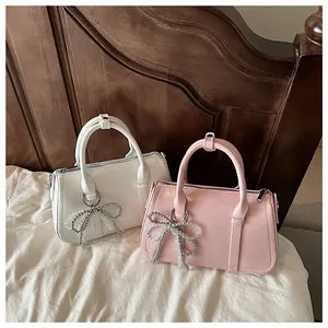 Nahaufnahme weißer und rosa Boston-Taschen mit Perlenbogen auf einem weichen Bettlaken