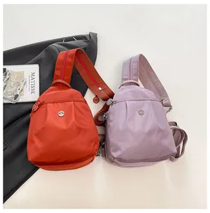 Close-up of lightweight nylon chest bags in orange and lilac with metal logos