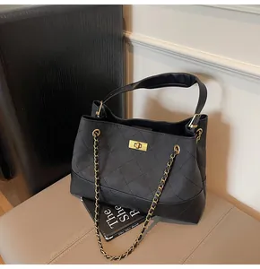 Close-up of black quilted leather tote bag with gold twist lock and chain strap detail