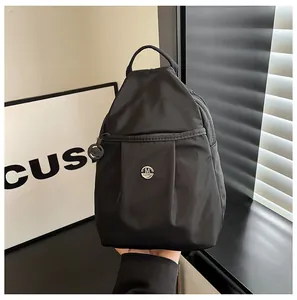 Detail of black nylon backpack featuring front pleated design and round metallic M logo