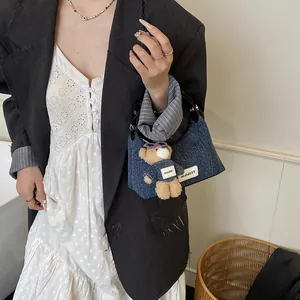 Blaue Denim-Halbmond-Unterarmtasche mit süßem Bärenanhänger getragen von einem Model