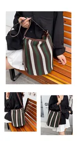 Detalle del bolso tipo saco de punto con rayas verdes y marrones y correa de cuero ajustable