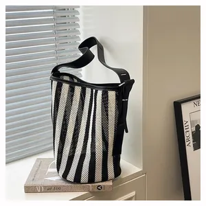 Detalle de bolso cubo tejido con rayas de cebra y correa de cuero negro con luz suave