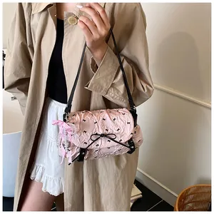 Detailed shot of pink pleated shoulder bag with black bows and a pearl ribbon charm