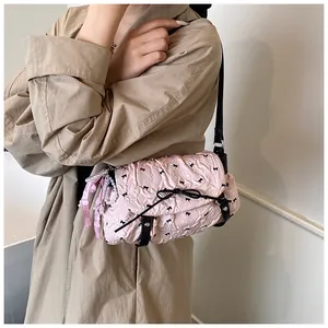 Detail view of pink pleated handbag with black bow print and pearl chain accessory
