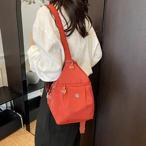Lightweight orange-red canvas backpack with a triangular shape and metal M logo detail