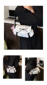 Detail of white pleated shoulder bag with black bow patterns and a pearl ribbon charm
