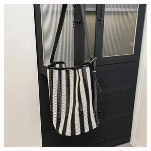 Detalle del bolso tipo cubo de malla con rayas verticales blancas y negras y correas