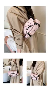 Detail of pink quilted shoulder bag with black bow patterns and elegant pearl charm