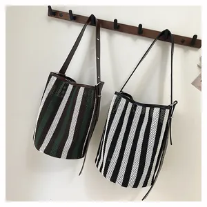 Detalle de bolsos hobo de malla a rayas colgados en ganchos con correas ajustables