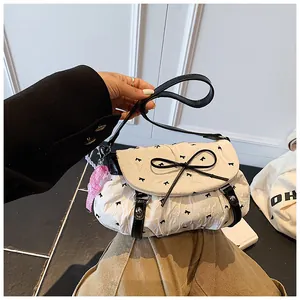 Close-up of stylish white handbag featuring black bow patterns and pink plaid charm