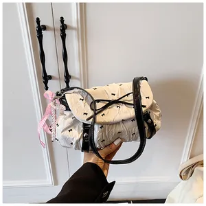 Close-up of white bow pattern handbag with pink ribbon and pearl charm detail