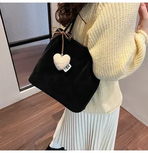 Detail of a black suede hobo bag with a plush heart charm and delicate bow accent