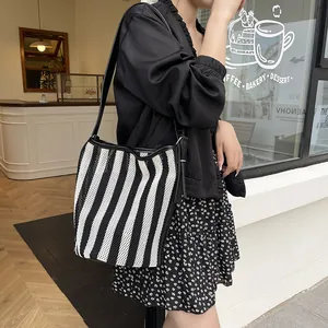 Bolso bombonera de tejido a rayas blanco y negro con correa de cuero en estilo callejero