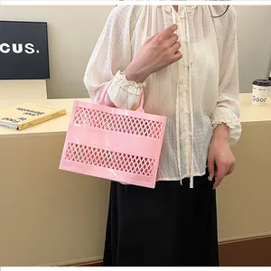 Pink hollow jelly basket bag with diamond grid pattern and integrated handle held by hand