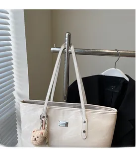 Detail of off-white tote bag with stone texture, metal logo and bear plush pendant