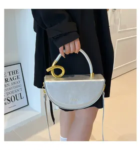 Detail of silver half-moon bag featuring a distinctive gold twist handle and fine strap