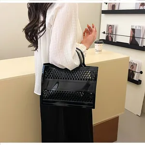 Fashionable black mesh jelly tote bag with wide horizontal band held by a model