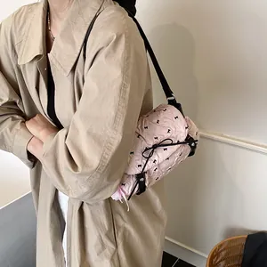 Pink pleated shoulder bag with black bow details shown on a model in a trench coat