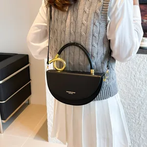 Chic black half-moon shoulder bag featuring a prominent gold metal ring handle detail