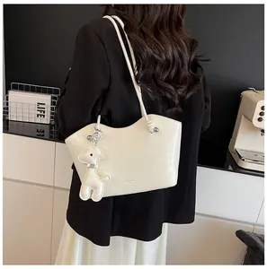 Detailansicht der cremefarbenen Leder-Tote-Bag mit Giraffen-Anhänger und Schulterriemen