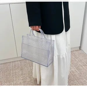 Detail of transparent PVC tote bag with textured geometric pattern held by a model