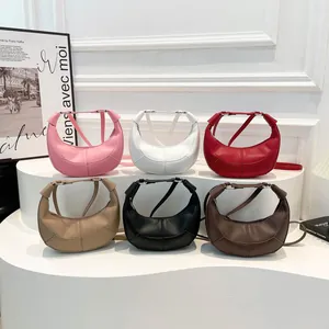 Sacs demi-lune minimalistes de différentes couleurs sur un présentoir de mode blanc