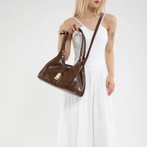 Deep brown glossy leather trapezoid shoulder bag with gold clasp and adjustable strap