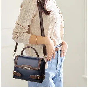 Navy blue lychee leather handbag with brown trim and gold hardware shown on a model