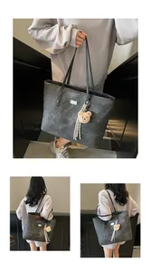 Detail view of stone-washed grey tote bag with plush bear charm and metallic brand plaque