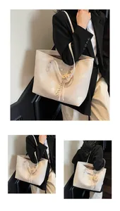 Detail view of large cream tote bag with fine leather texture and cute bear charm